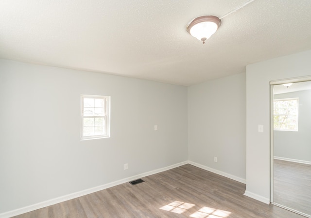 unfurnished room featuring a textured ceiling, hardwood / wood-style flooring, and plenty of natural light