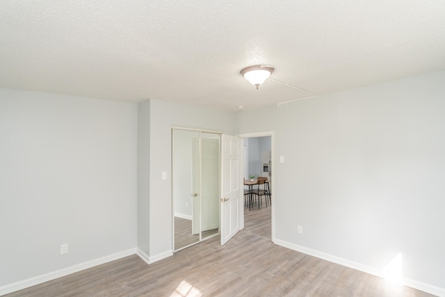 spare room with a textured ceiling and light hardwood / wood-style flooring