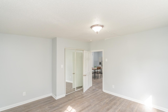 spare room featuring wood finished floors, baseboards, and a textured ceiling