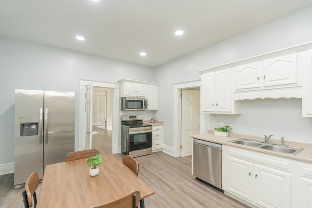 kitchen with appliances with stainless steel finishes, light hardwood / wood-style floors, white cabinetry, and sink