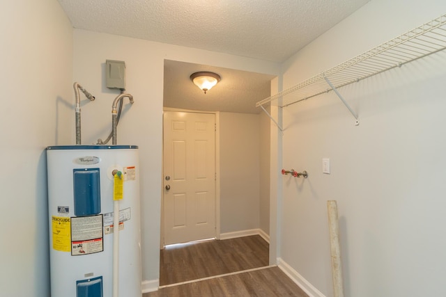 laundry room featuring water heater, wood finished floors, a textured ceiling, and baseboards
