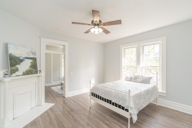 bedroom featuring wood finished floors, baseboards, and a ceiling fan