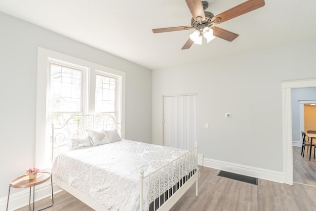 bedroom featuring wood finished floors, baseboards, and a ceiling fan