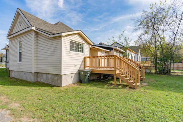 rear view of house featuring a deck, a yard, stairway, and a shingled roof