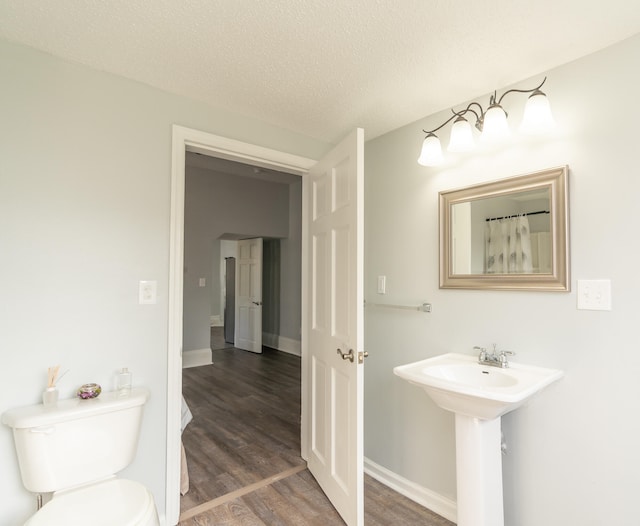 bathroom with sink, toilet, wood-type flooring, and a textured ceiling