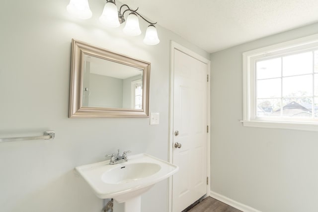 bathroom with a sink, baseboards, wood finished floors, and a chandelier