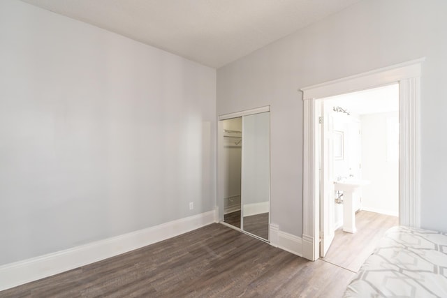 unfurnished bedroom with dark wood-style floors, a closet, and baseboards