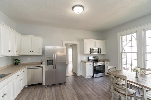 kitchen with stainless steel appliances, dark wood-style flooring, white cabinetry, and a textured ceiling