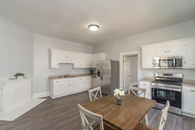 kitchen with dark wood-type flooring, white cabinets, stainless steel appliances, and a textured ceiling