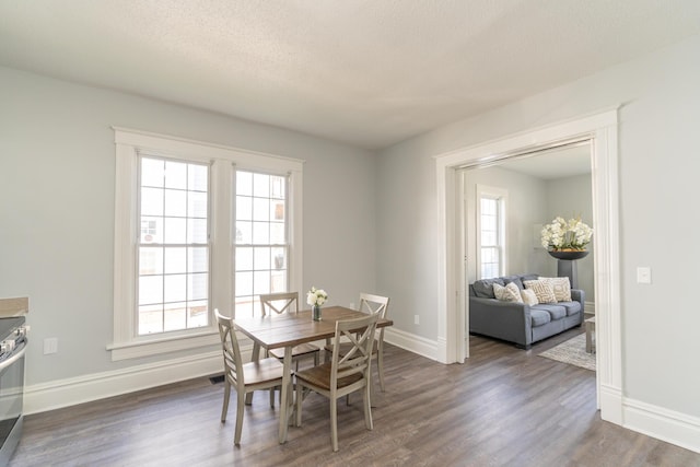 dining area with dark wood-type flooring, baseboards, and a textured ceiling