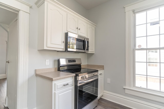 kitchen with plenty of natural light, dark hardwood / wood-style flooring, white cabinetry, and appliances with stainless steel finishes