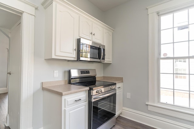 kitchen featuring appliances with stainless steel finishes, baseboards, healthy amount of natural light, and white cabinetry