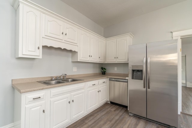 kitchen featuring stainless steel appliances, a sink, dark wood-style floors, white cabinetry, and light countertops