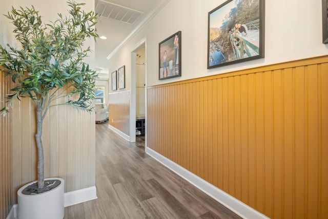 corridor featuring crown molding, hardwood / wood-style floors, and wood walls