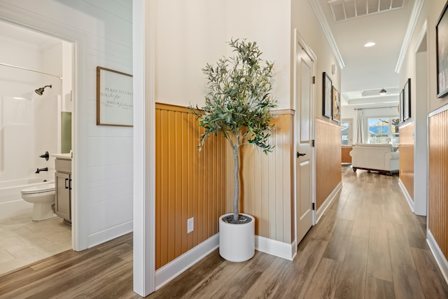 hall featuring wood walls, wood-type flooring, and ornamental molding