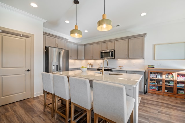 kitchen featuring a kitchen island with sink, crown molding, light stone counters, dark hardwood / wood-style flooring, and stainless steel appliances