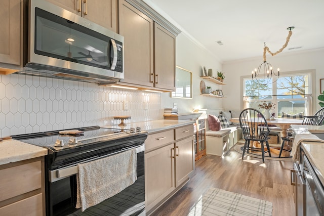 kitchen with crown molding, dark hardwood / wood-style flooring, light stone counters, and appliances with stainless steel finishes