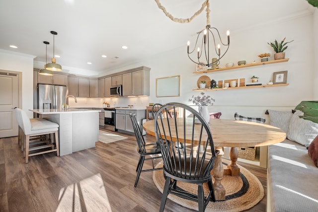 dining area with a chandelier, dark hardwood / wood-style floors, ornamental molding, and sink