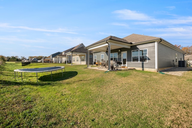 back of property featuring a lawn, a trampoline, central air condition unit, ceiling fan, and a patio area