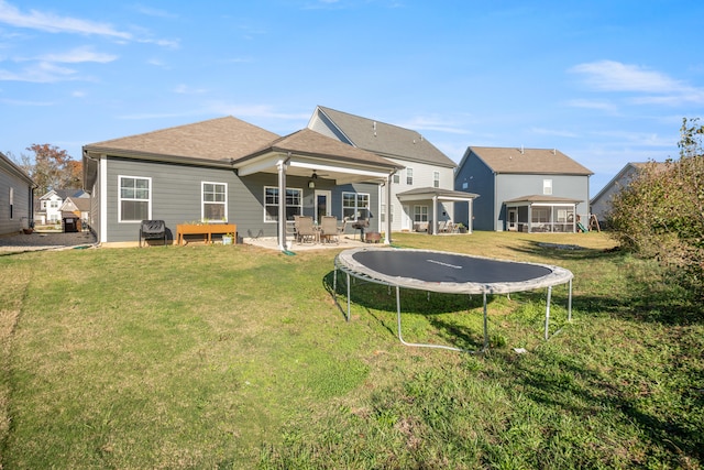 back of house with ceiling fan, a trampoline, a patio, and a yard