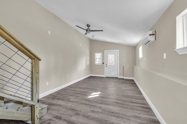 foyer featuring a wall mounted air conditioner, ceiling fan, hardwood / wood-style floors, and vaulted ceiling