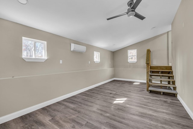 basement featuring an AC wall unit, wood-type flooring, and ceiling fan