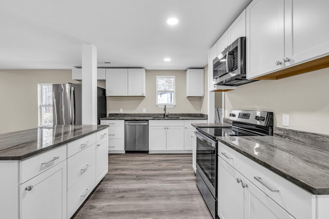 kitchen featuring white cabinets, stainless steel appliances, and dark stone countertops