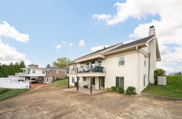 rear view of house with a patio, a balcony, and central AC unit