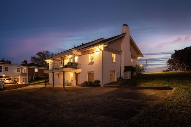 back house at dusk with a balcony and central AC