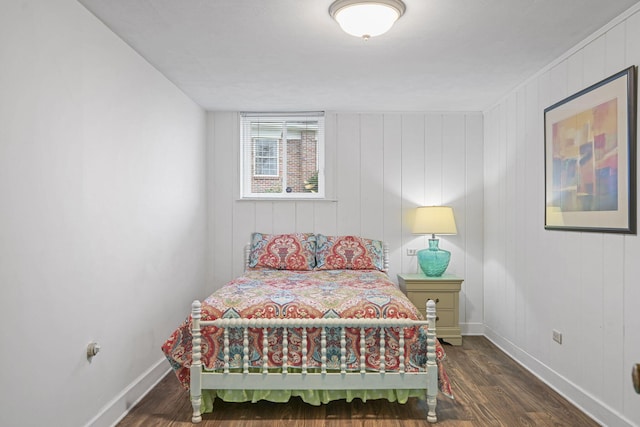 bedroom featuring wooden walls and dark hardwood / wood-style floors