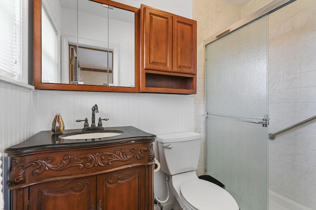 bathroom featuring vanity, a shower with shower door, and toilet