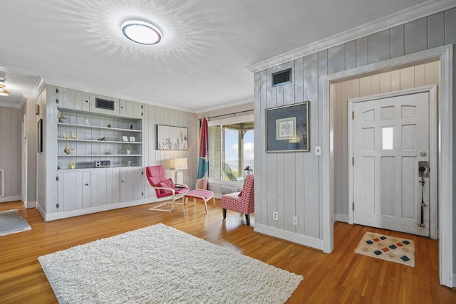 foyer featuring light hardwood / wood-style floors, ornamental molding, and wood walls