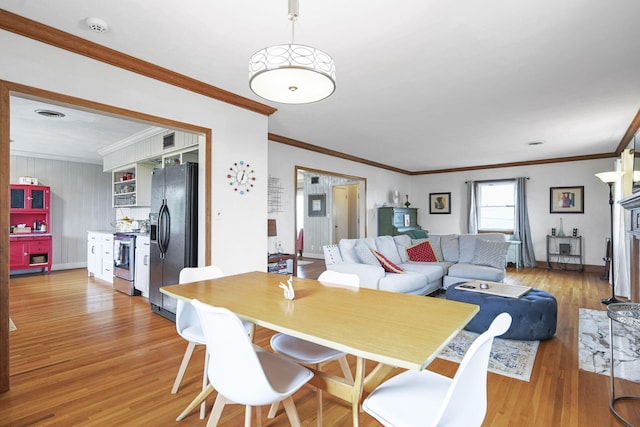 dining area featuring ornamental molding and light hardwood / wood-style flooring