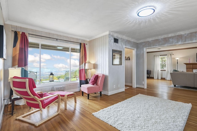 living area with hardwood / wood-style flooring and ornamental molding