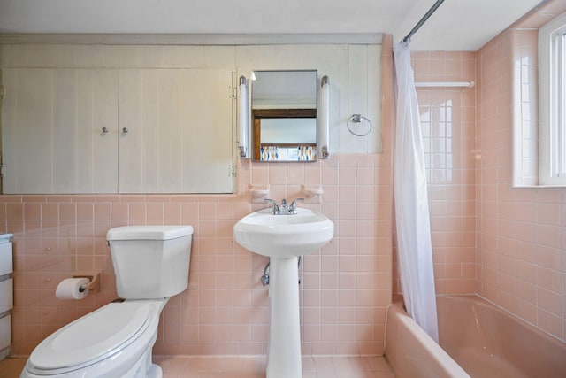 bathroom with tile patterned floors, shower / bathtub combination with curtain, a healthy amount of sunlight, and tile walls