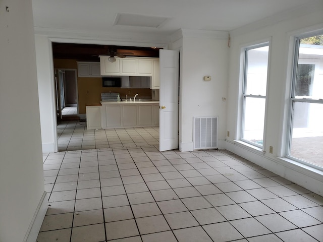 interior space featuring crown molding, plenty of natural light, light tile patterned floors, and sink