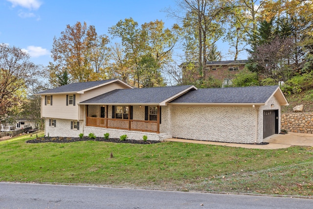 tri-level home with covered porch, a garage, and a front lawn