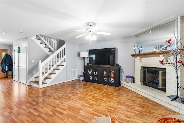 living room with hardwood / wood-style flooring, ceiling fan, a fireplace, and a textured ceiling