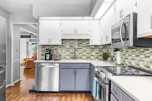 kitchen featuring white cabinetry, sink, stainless steel appliances, tasteful backsplash, and light hardwood / wood-style floors