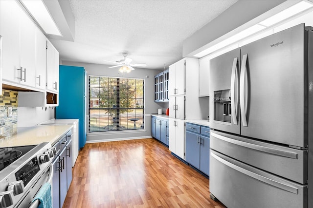 kitchen with white cabinets, ceiling fan, light wood-type flooring, and appliances with stainless steel finishes