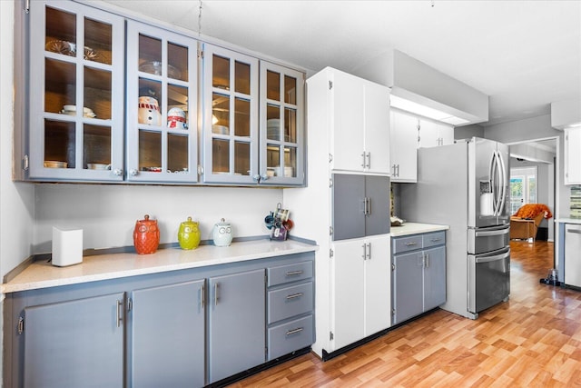 kitchen featuring gray cabinetry, stainless steel fridge, light wood-type flooring, and white cabinetry