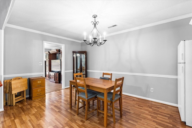 dining room with a textured ceiling, light wood-type flooring, an inviting chandelier, and crown molding