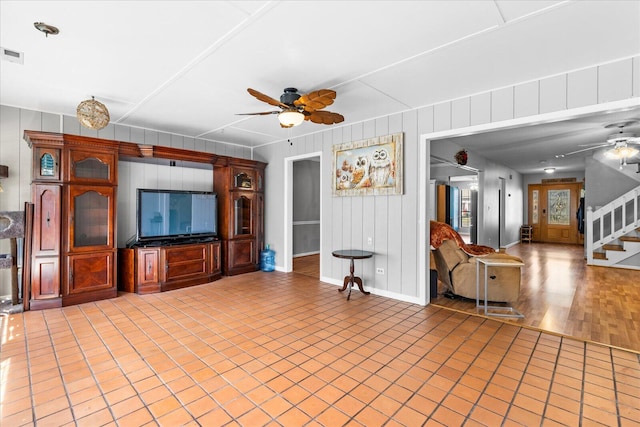 unfurnished living room with hardwood / wood-style flooring, ceiling fan, and wood walls