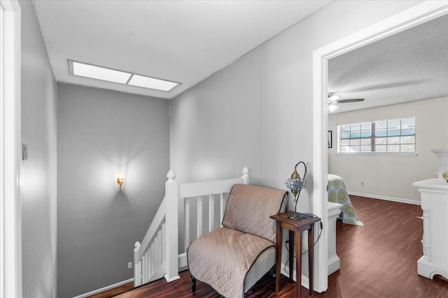 sitting room with a textured ceiling, a skylight, ceiling fan, and dark hardwood / wood-style floors