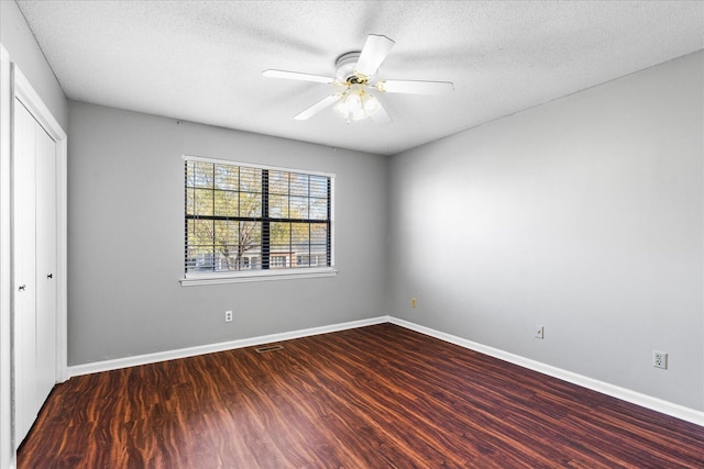 empty room featuring a textured ceiling, ceiling fan, and dark wood-type flooring