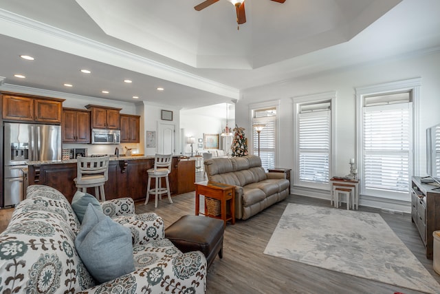 living room with a tray ceiling, crown molding, ceiling fan, and dark hardwood / wood-style floors