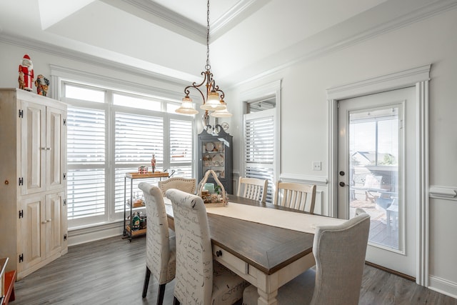 dining area with a notable chandelier, dark hardwood / wood-style floors, a raised ceiling, and ornamental molding