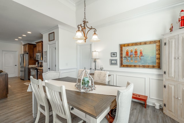 dining area with light hardwood / wood-style floors, ornamental molding, and an inviting chandelier