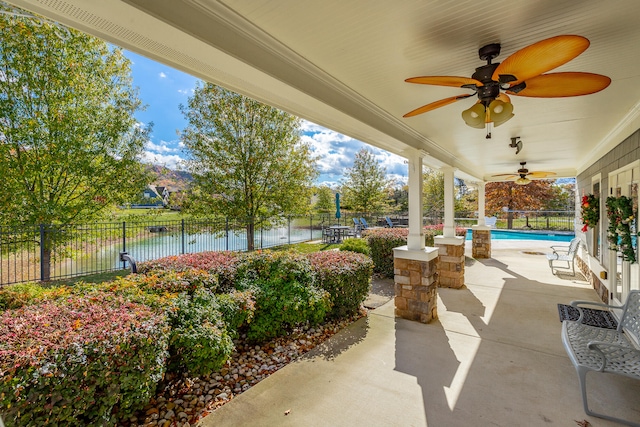 view of patio featuring a fenced in pool, ceiling fan, and a water view