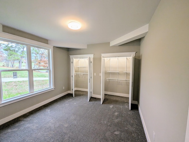 unfurnished bedroom with dark colored carpet, a spacious closet, and a closet